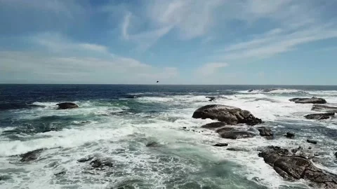 Rising tilt down shot on ocean with large boulders in water Stock Footage 155461481