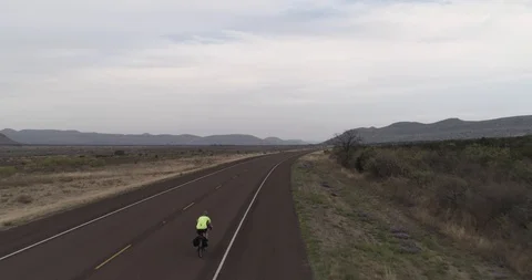 Rising up tracking a cyclist in overcast, desolate environment drone aerial 4K Stock Footage 111316264