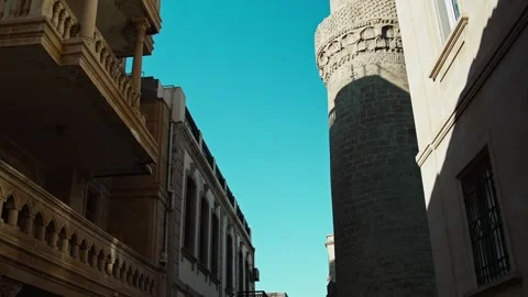 Rising View of Historic Stone Tower Between Buildings on a Clear Day Stock Footage 338244627