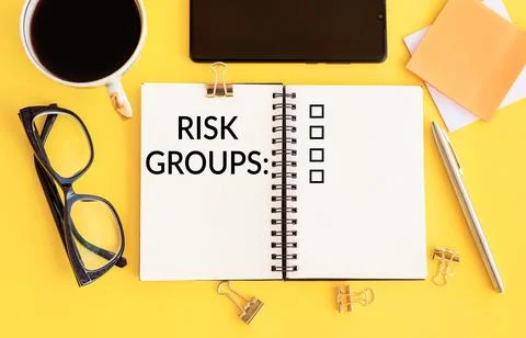 RISK GROUPS text is written in a notebook on yellow table with coffee, glas.. Stock Photos