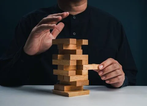 Risk management and decision making concept with hand removing wooden block.. Stock Photos