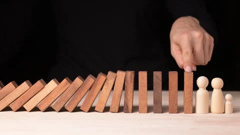 Risk Management in Decision Making Hand Stopping Falling Dominos During a Stock Footage 296262364