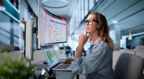 Risk Manager Carefully Analyzing Financial Data On Wide Curved Screen. Stock Photos