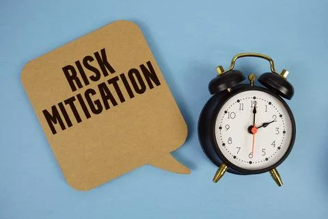 Risk Mitigation text with alarm clock on blue background Stock Photos