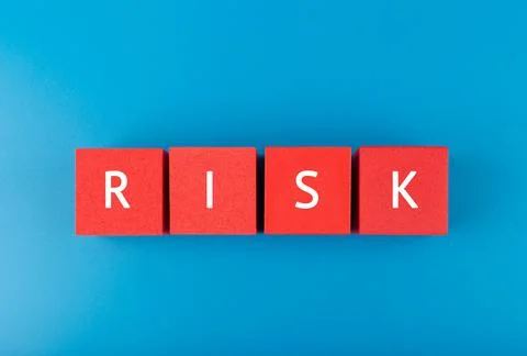 Risk single word written on red cubes against blue background Stock Photos