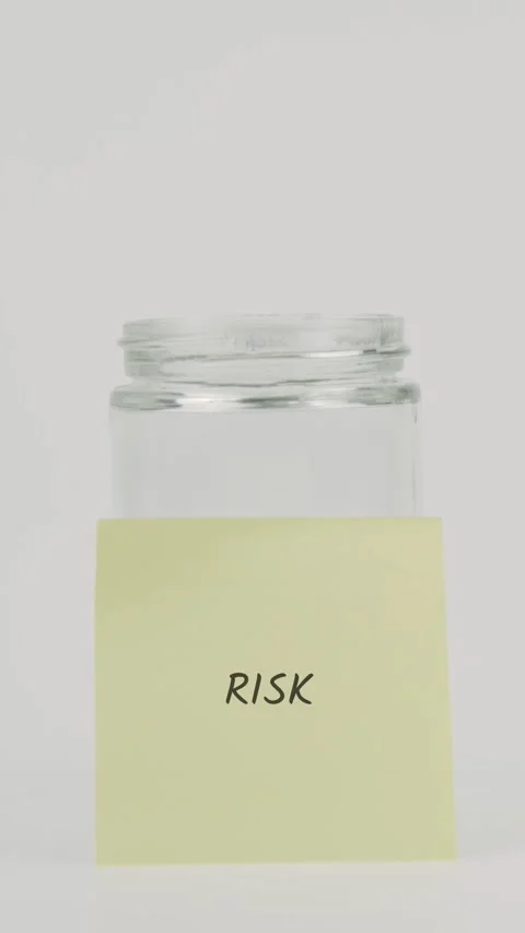 Risk text or word on yellow sticky note attached to glass jar with hand Stock Footage 311782581