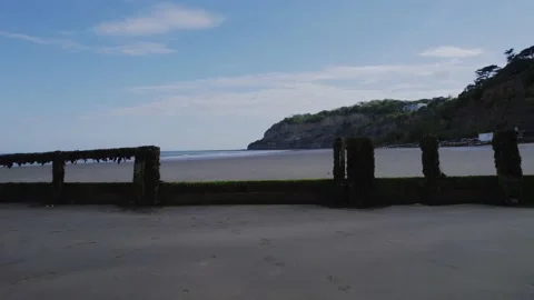 Risky flying high speed drone shot past object pier at the beach towards the sky Stock Footage 167769625