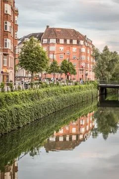 The river in Aarhus flows gently through the city and buildings reflecting in Stock Photos