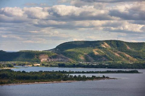 River against a cloudy sky with clouds and forest. Stock Photos