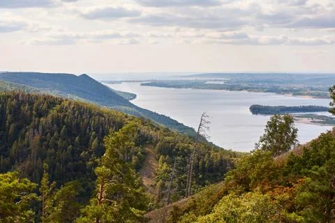 River against a cloudy sky with clouds and forest. Stock Photos