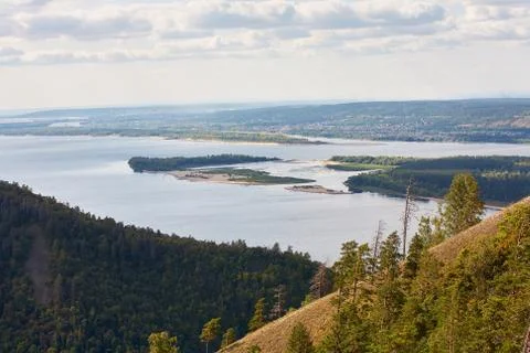 River against a cloudy sky with clouds and forest. Stock Photos