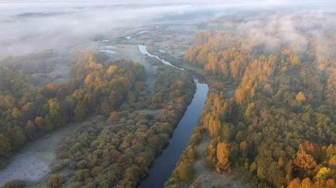 A river among fields and forests in clouds and fog with the first frosts Foto stock