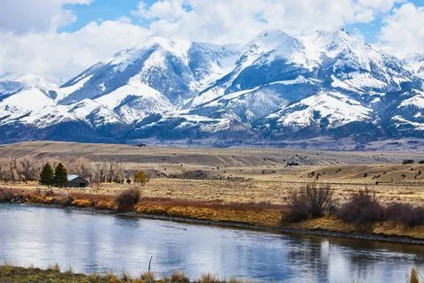 River and fields next to stunning snowy mountains 스톡 사진