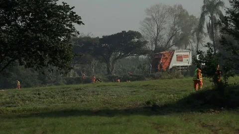 River Bank Pollution Cleaning: far view of cleaning workers next to trash truck Stock Footage 78934366