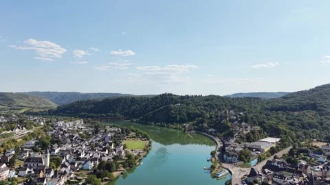 A river bend separates village rooftops from wooded slopes 動画素材 342339955