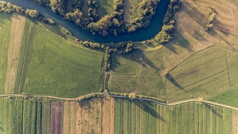 River bend surrounded by fields from bird's eye view. Stock Photos