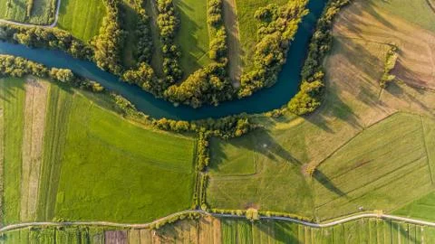 River bend surrounded by fields from bird's eye view. Stock Photos