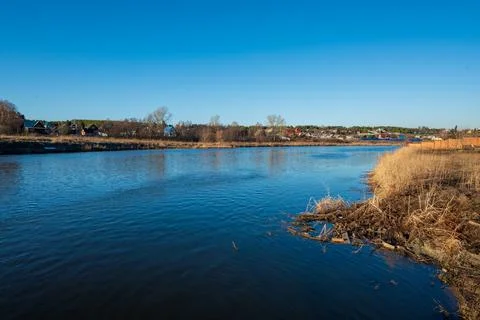 A river with a blue sky and a small town in the background Stock Photos