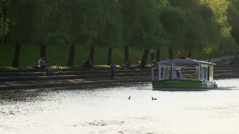 River boat going past sitting people along river bank 動画素材 155649722