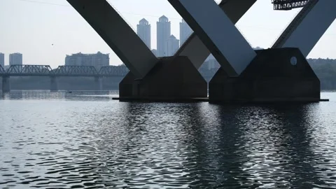 A river bridge's structural supports over a flowing water. Quiet atmosphere Vídeos de archivo 296084516