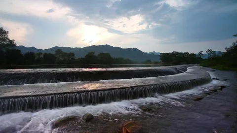 A river cascades over small dams in a mountainous landscape Stock Footage 312303185