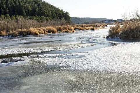 River covered with first ice and snow in late autumn or early winter forest Foto stock