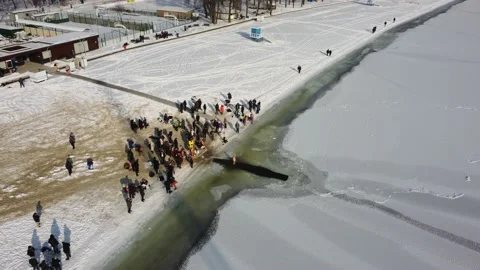 River is covered with ice, people enter the cold water, cross themselves Stock Footage 221989377