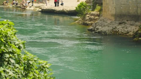 River crossing the city of Mostar with its bridge and tourists, in Bosnia Stock Footage 241676448