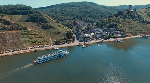 A river cruise arrives at a small German town along the Mosel River Stock Footage