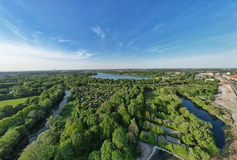 A river cutting through trees, cityscape nearby, under a cloudy sky Hanover Stock Photos