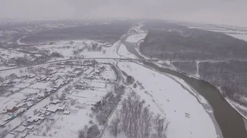 The river divides a small town and forest, aerial photography, fog Stock Footage 85571657