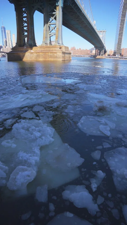 River edge under Manhattan Bridge is partially frozen in the morning at Brooklyn Vídeo Stock 336828277