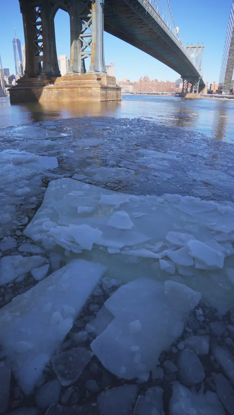 River edge under Manhattan Bridge is partially frozen in the morning at Brooklyn Vídeos de archivo 336831077