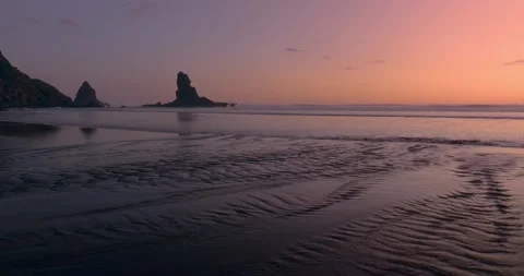 River estuary flowing over the sand into the ocean at sunset. Anawhata, Piha, Stock Footage 280314170