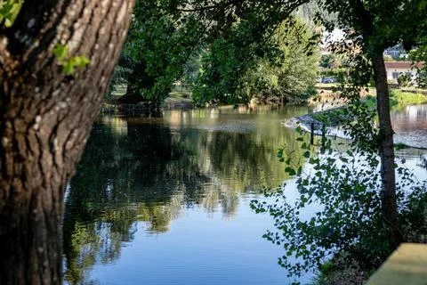 A river featuring a small stone dam with water cascading over the edge Stock Photos