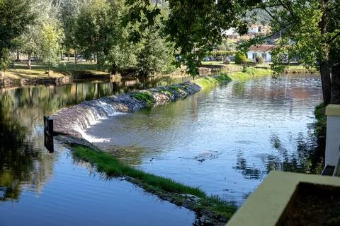 A river featuring a small stone dam with water cascading over the edge Stock Photos