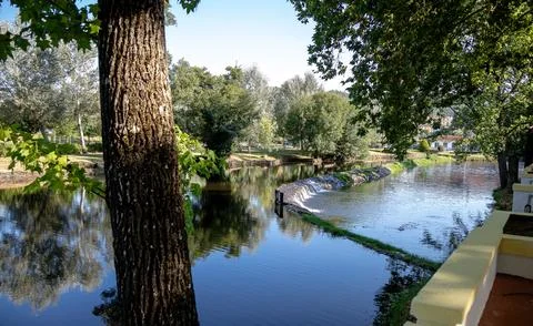 A river featuring a small stone dam with water cascading over the edge Stock Photos