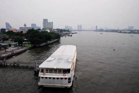 A river ferry stands at the pier on the Chao Phraya River in the evening. Stock Photos