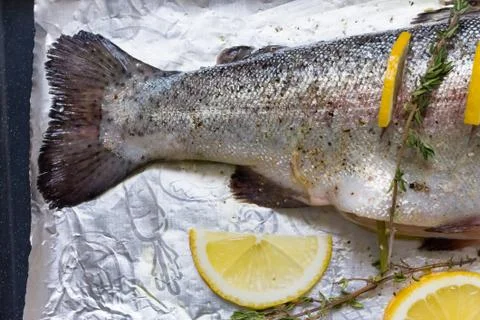 River fish trout on a baking sheet stuffed with lemon wedges and a sprig of Stock Photos