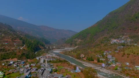 A river flowing between the mountains and a beautiful village settled there Stock Footage 307675330