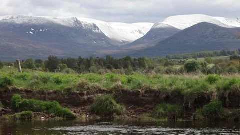 River flowing by distant snow-capped Cairngorm mountains, Scotland Stock Footage 335540171