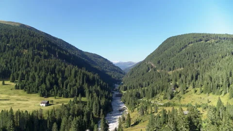 River flowing down valley in the alps surrounded by tall hills and forests Stock Footage 153300821