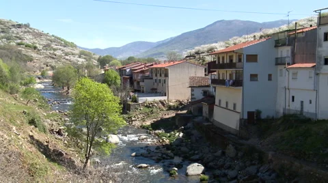 River flowing down by village, with cherry tree plantations on slopes Stock Footage 49054573