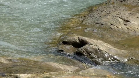 River flowing through the crevices of river rocks 스톡 동영상 336878761