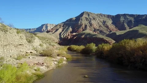 River flowing through desert mountain landscape, low aerial with mountain in bac Stock-Footage 83051751