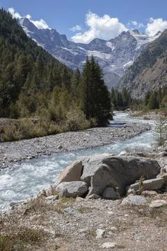 River flowing through gran paradiso valley with mountains Stock Photos