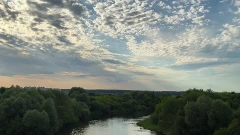 River flowing through green forest under cloudy sky with sun rays Видео 338201336