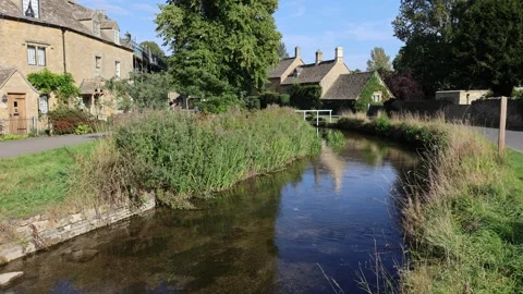 River flowing through Lower Slaughter village in the Cotswolds, UK Stock Footage 322516141