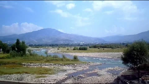 River flowing through rocky valley with mountains in background Stock Footage 346540227
