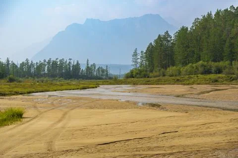 River flowing through sandy valley with mountain backdrop Stock Photos